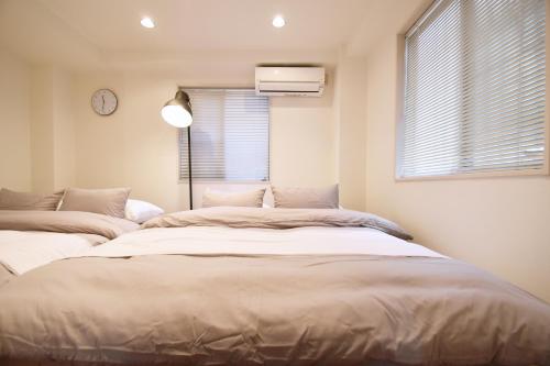 two beds in a room with a window and a clock at TERRACE HOUSE Shibuya Maruyamacho in Tokyo