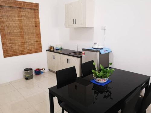 uma cozinha com uma mesa preta e cadeiras e uma cozinha com um frigorífico em Cozy 3 Bedrooms Apartment Langkawi em Kuah