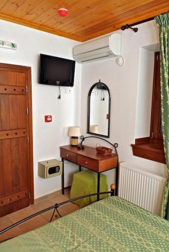 a bedroom with a bed and a desk and a tv at Archontiko Papoutsi in Mouresi