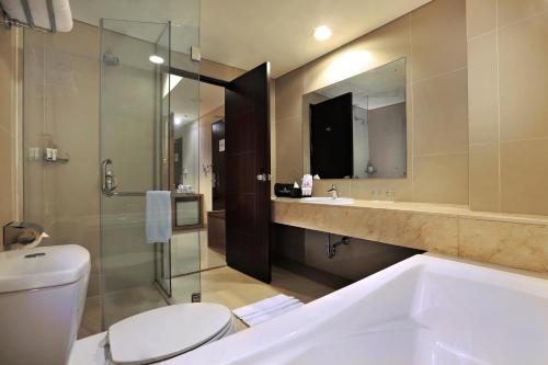 a bathroom with a tub and a toilet and a sink at Atria Residences Gading Serpong in Serpong