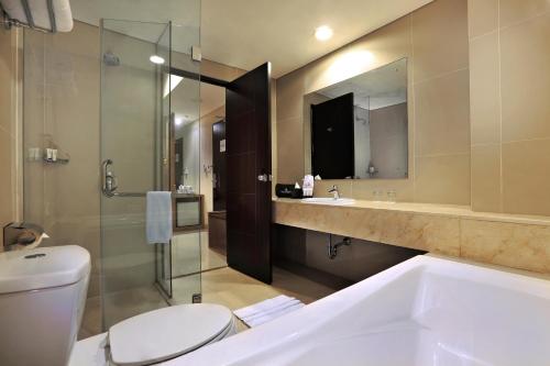 un bagno con vasca, WC e lavandino di Atria Residences Gading Serpong a Serpong