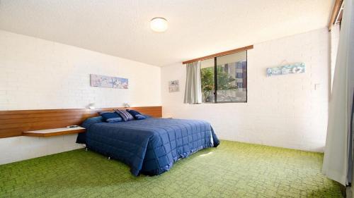 - une chambre avec un lit bleu et une fenêtre dans l'établissement By The Sea Unit 4 13 Esplanade Kings Beach, à Caloundra