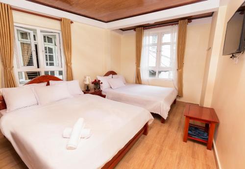 two beds in a room with two windows at Bình Đào Hotel - Khách sạn ngay trung tâm giá rẻ in Da Lat