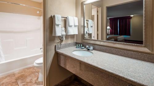 a bathroom with a sink and a mirror and a toilet at Best Western Pine Springs Inn in Ruidoso Downs