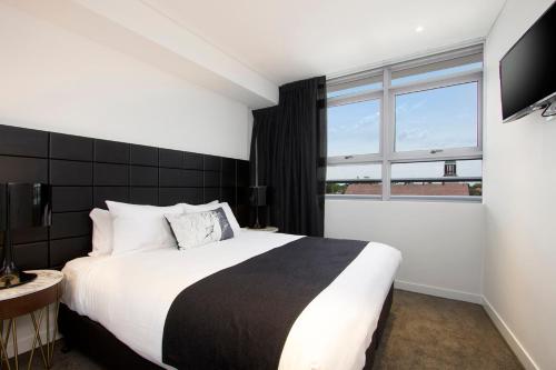 a bedroom with a large bed and a large window at Silkari Suites at Chatswood in Sydney