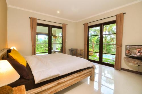 ein Schlafzimmer mit einem Bett und zwei großen Fenstern in der Unterkunft Amara Giri I in Ubud