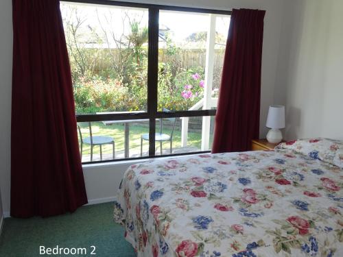 a bedroom with a bed in front of a window at Cabourne Cottage in Hamilton