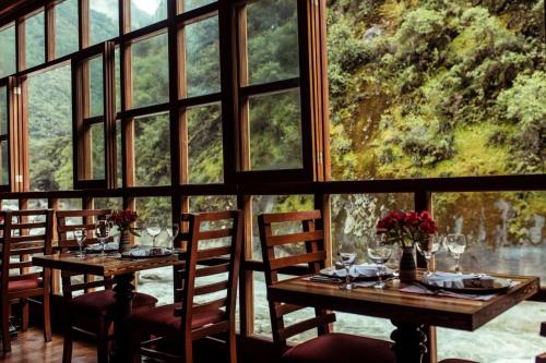 a dining room with two tables and windows at Casa del Sol Machupicchu in Machu Picchu
