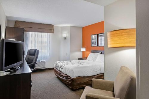 a hotel room with a bed and a flat screen tv at Sleep Inn DeWitt - Lansing North in DeWitt