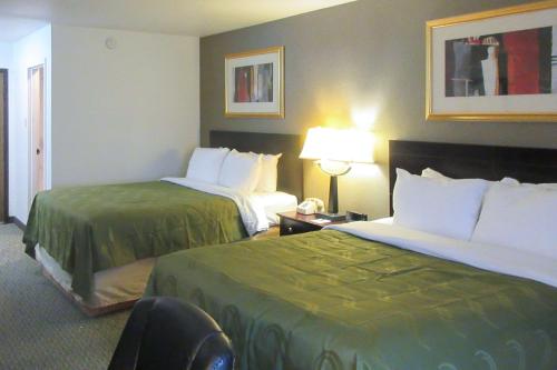 a hotel room with two beds and a chair at Quality Inn Longmont in Longmont