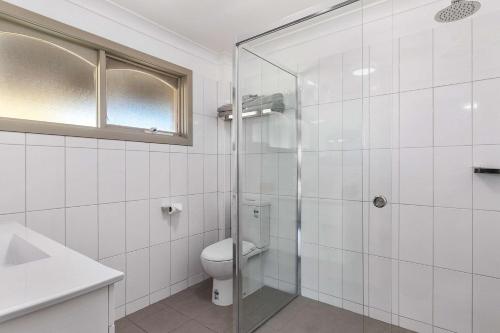 W łazience znajduje się toaleta i przeszklony prysznic. w obiekcie Quality Inn Carriage House w mieście Wagga Wagga