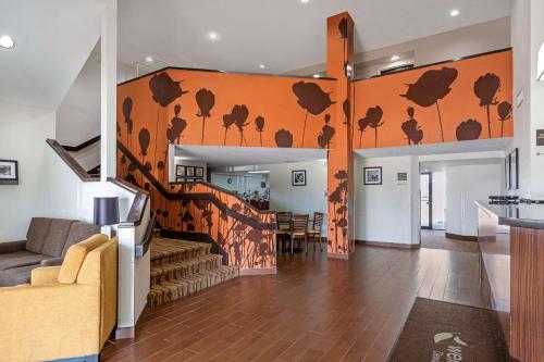 a living room with an orange wall with chickens on it at Sleep Inn DeWitt - Lansing North in DeWitt