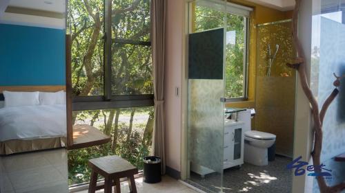a bedroom with a bed and a bathroom with a window at Toptai Homestay in Kenting
