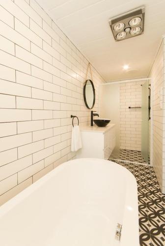 a white bathroom with a tub and a sink at The Manor Basket Range in Basket Range