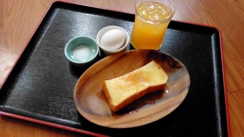 a plate with a piece of bread and a glass of orange juice at ホテルヴィラコスタ Adult Only 男塾ホテルグループ in Hikone