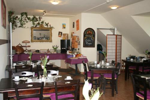 ドレスデンにあるHotel am Waldschlösschen - Brauhausの木製テーブルと紫色のテーブルと椅子が備わるレストラン