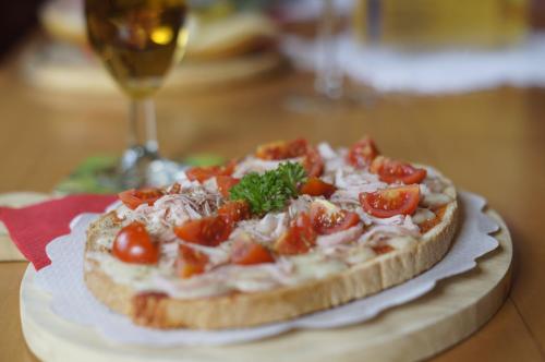 a pizza sitting on a table with a glass of wine at Hotel Garni Schneider in Lutago
