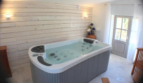 bañera en una habitación con pared de madera en Le Bastidon de CUCURON, en Cucuron