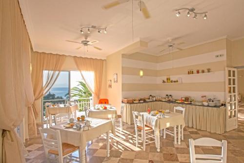 a room with tables and chairs and a kitchen at Aurora Beach Hotel in Agios Ioannis Peristeron