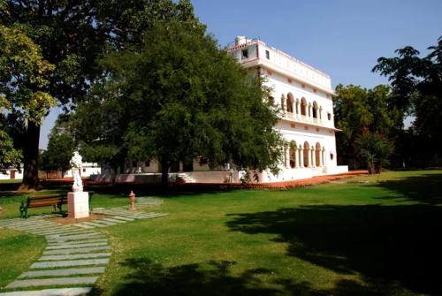 a large white building with a fire hydrant in a park at Hotel Bijay Niwas Palace in Bijainagar