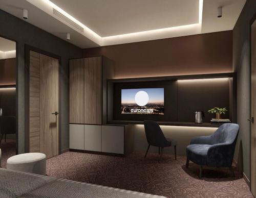 a hotel room with a tv and a bed and chairs at Best Western Plus Paradise Hotel Dilijan in Dilijan