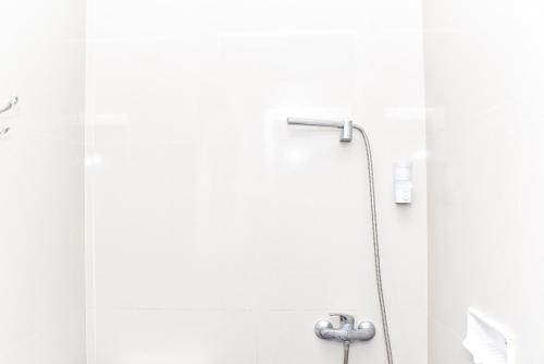 a shower with a hose in a bathroom at RedDoorz near Alun Alun Wonosobo in Wonosobo
