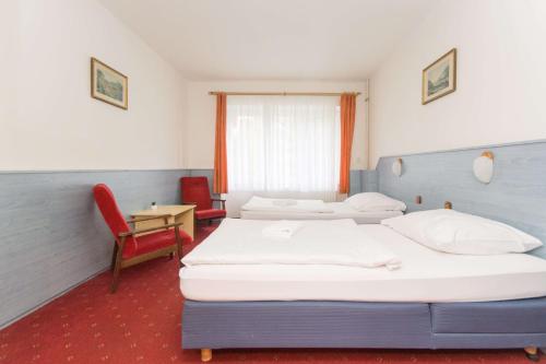 une chambre d'hôtel avec deux lits et une chaise dans l'établissement Sport Hotel Gejzirpark, à Karlovy Vary