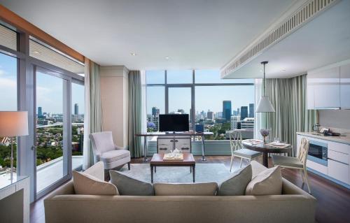 a living room filled with furniture and a large window at Oriental Residence Bangkok - SHA Certified in Bangkok