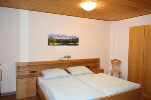 een slaapkamer met een groot bed met een houten hoofdeinde bij Haus Kohler Bernhard in Nova Levante