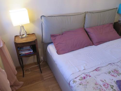 a bed with pink pillows and a lamp on a table at CAVOUR citra0461 in Genoa