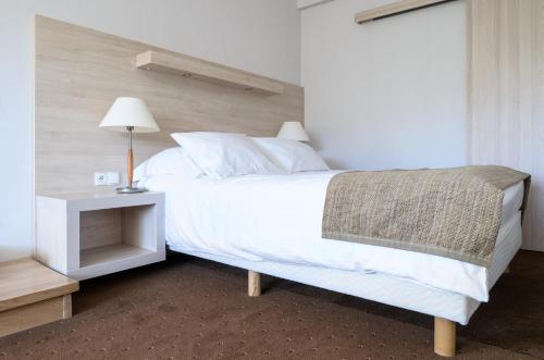 a bedroom with a white bed and a night stand at Kormoran Medispa in Rowy
