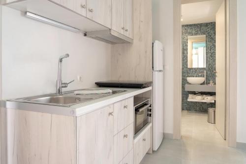 a white kitchen with a sink and a refrigerator at Paradisos in Frangokastello