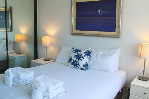 a bedroom with a white bed with towels on it at Cairns Aquarius in Cairns