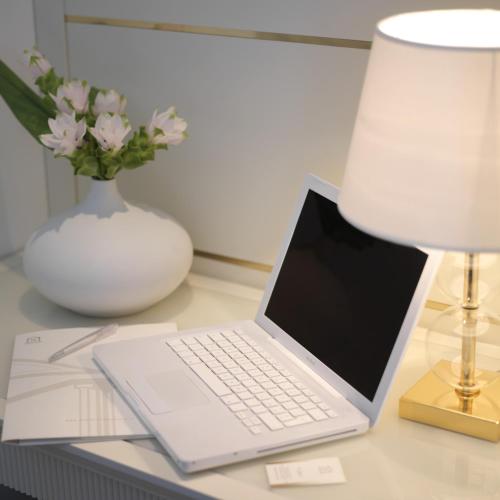 a laptop computer sitting on top of a desk with a lamp at Hotel Tiffany's in Riccione
