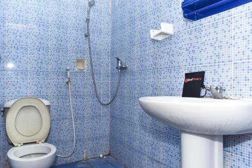 a blue tiled bathroom with a toilet and a sink at RedDoorz Plus @ Tirta Kencana Hotel in Ambon