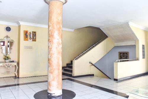 a hallway with a column and stairs in a building at RedDoorz Plus @ Tirta Kencana Hotel in Ambon