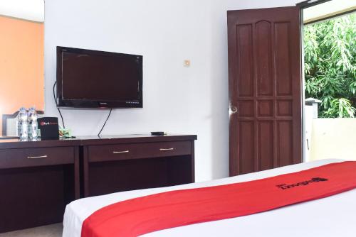 a bedroom with a bed with a flat screen tv at RedDoorz Plus @ Tirta Kencana Hotel in Ambon