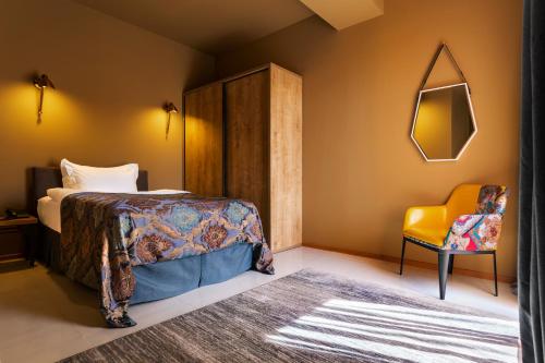 a bedroom with a bed and a yellow chair at Brim Hotel in Tbilisi City