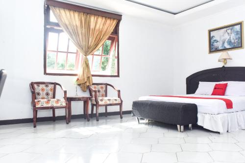 a bedroom with a bed and two chairs at RedDoorz Plus @ Tirta Kencana Hotel in Ambon