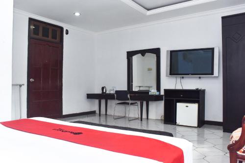 a bedroom with a bed and a desk and a tv at RedDoorz Plus @ Tirta Kencana Hotel in Ambon