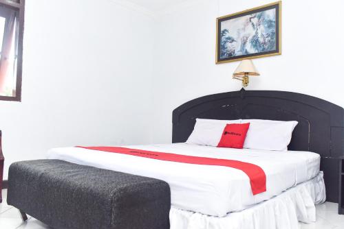 a bedroom with a large bed with a red pillow at RedDoorz Plus @ Tirta Kencana Hotel in Ambon