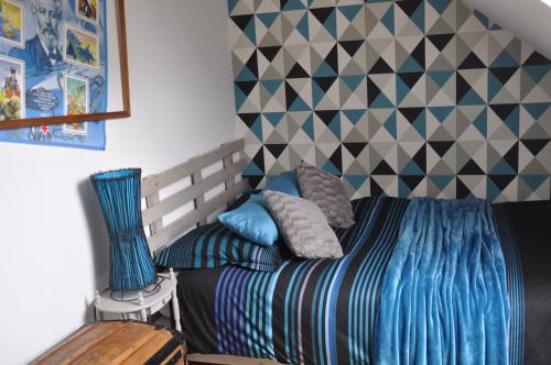 a bedroom with a bed with a blue comforter at Chambres à la campagne au nord d' Amiens avec salle de bain privative in Rubempré