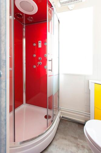 La salle de bains est pourvue d'une douche aux murs rouges. dans l'établissement Chateau Marieville, à Bonneuil-Matours