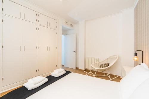 a white bedroom with a bed and a chair at Trendy Homes Almería in Almería