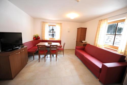 ein Wohnzimmer mit einem roten Sofa und einem Tisch in der Unterkunft Apartments Restaurant Rusctlea in Wolkenstein in Gröden