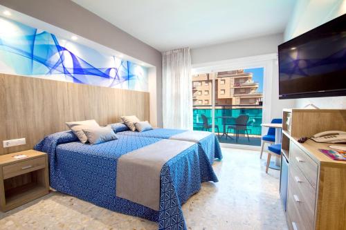 a hotel room with a bed and a television at Hotel Servigroup Koral Beach in Oropesa del Mar