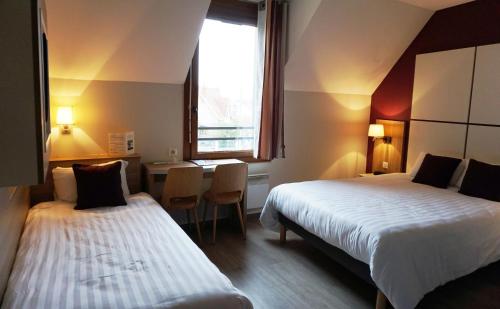 Cette chambre comprend deux lits, une table et une fenêtre. dans l'établissement Hôtel Restaurant Du Parc de la Colombière, à Dijon