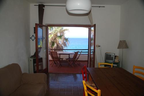 - un salon avec une table et une vue sur l'océan dans l'établissement Waterfront Apartments Bosa Porto Alabe, à Tresnuraghes