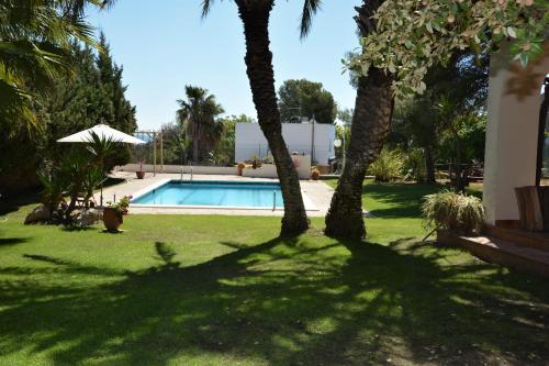 a shady yard with palm trees and a swimming pool at Villa Sitges Colibri at 10 min Walk Beaches - Center City Amaizing Garden Pool XXL Private Tenis Piste in Vilanova i la Geltrú