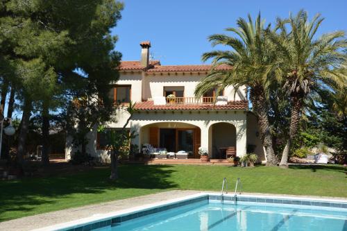 a villa with a swimming pool in front of a house at Villa Sitges Colibri at 10 min Walk Beaches - Center City Amaizing Garden Pool XXL Private Tenis Piste in Vilanova i la Geltrú